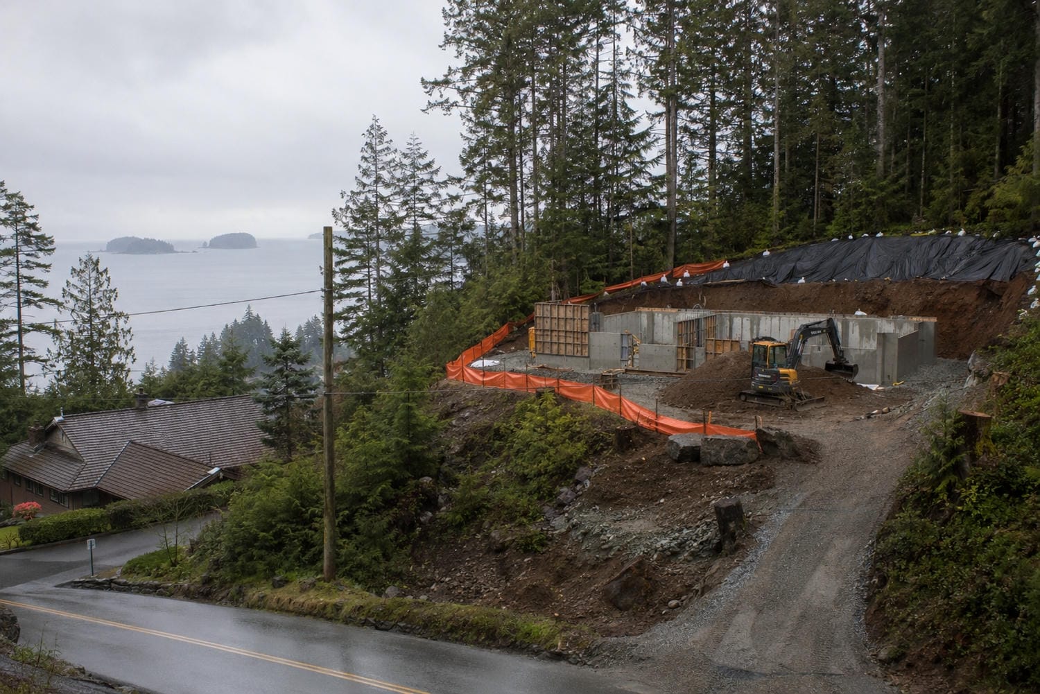 Steep forested slope above a Vancouver area street with a level bench cut into the hillside for a new house