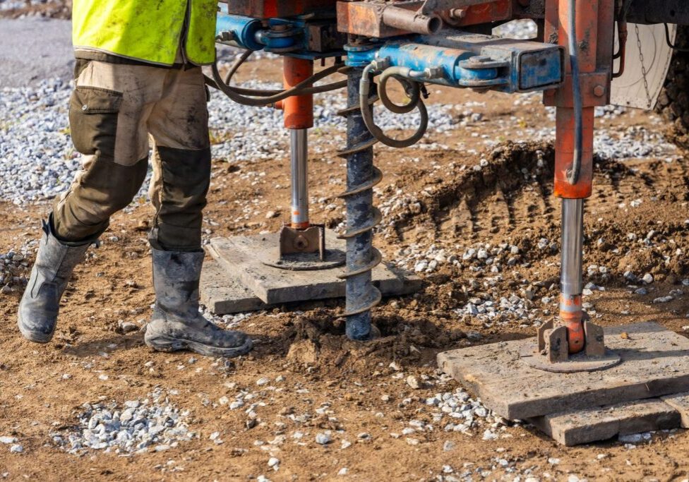 Compact drill rig taking soil samples on a flat residential lot during a custom home soils test in the BC Lower Mainland.