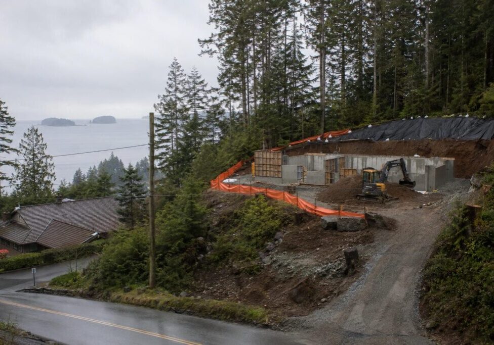 Steep forested slope above a Vancouver area street with a level bench cut into the hillside for a new house